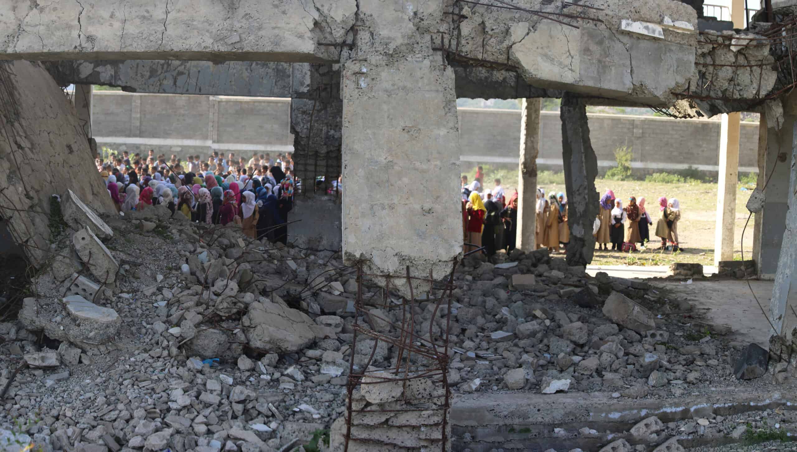 Yemeni children stand in line in the morning on the first day of school for the new year inside their school which destroyed by the war in Taiz city, Yemen