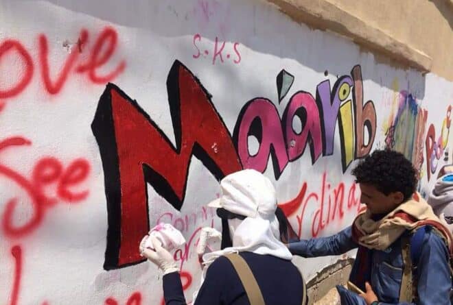 بين شعاري «النصر» و «الهزيمة» شابة يمنية تبرز شعار «السلام» في مأرب