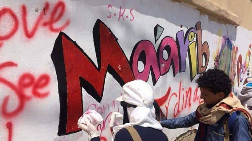 بين شعاري «النصر» و «الهزيمة» شابة يمنية تبرز شعار «السلام» في مأرب